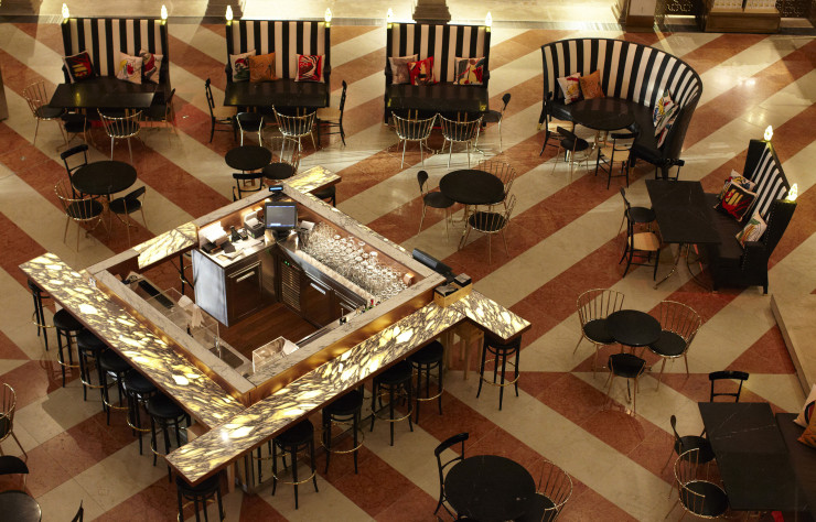 Répartis autour du bar central en marbre noir, les canapés à hauts dossiers délimitent l’espace du restaurant au sein de l’atrium.