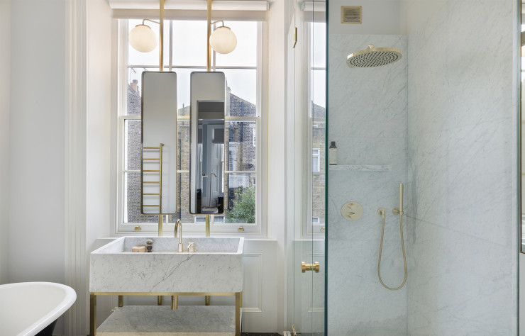 Dans la salle de bains du 1er étage, la vasque en marbre de Carrare non-poli accompagne la baignoire victorienne en fonte. Dessinés par Gundry & Ducker, les luminaires et les miroirs en laiton agrémentent cet ensemble élégant.
