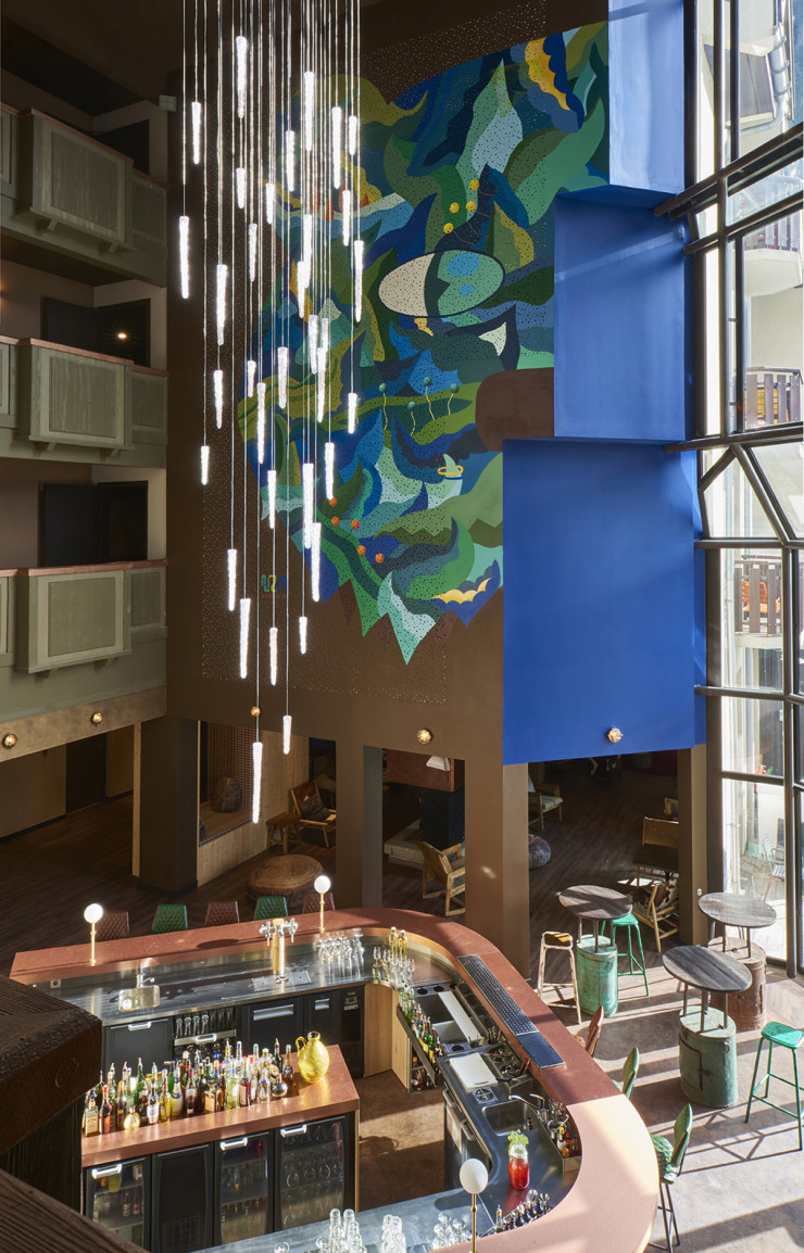 Au-dessus du bar, la fresque signée v2m anime l’atrium et répond au lustre fabriqué sur-mesure.