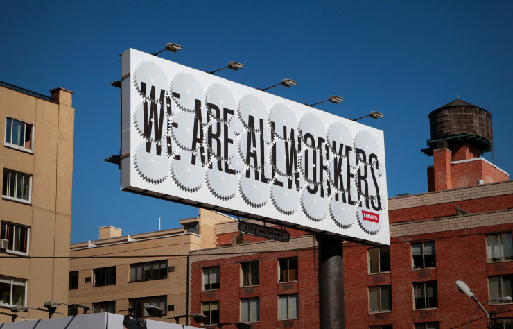 Le panneau d’affichage de la marque Levi’s, installé à SoHo (New York), expose la phrase « We are all workers » (nous sommes tous des travailleurs) en brisant et reconstruisant constamment la typographie placée sur des roues dentées qui tournent.