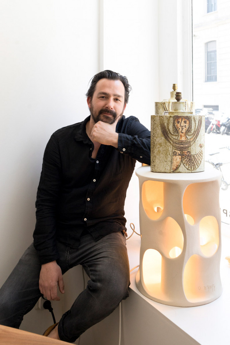 Benjamin Desprez pose près d’une lampe de Roger Capron présentée sur une table lumineuse de Guy Bareff (représenté en exclusivité par la galerie).