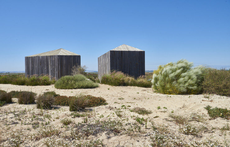 Manuel Aires Mateus, ponte de l’architecture lisboète, a déposé deux drôles de huttes polyédriques en bois recyclé au bord des eaux dormantes de la lagune du Sado.