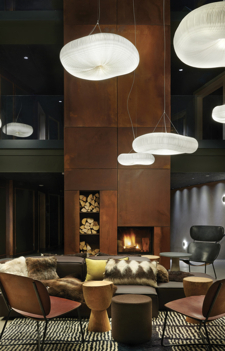 Dans le lobby, la cheminée  fait face au sofa Extrasoft de Piero Lissoni, aux chauffeuses Noti, aux sièges en cuir Functional, aux tabourets Tam Tam de Pols Potten et aux suspensions Cloud de Molo Design.