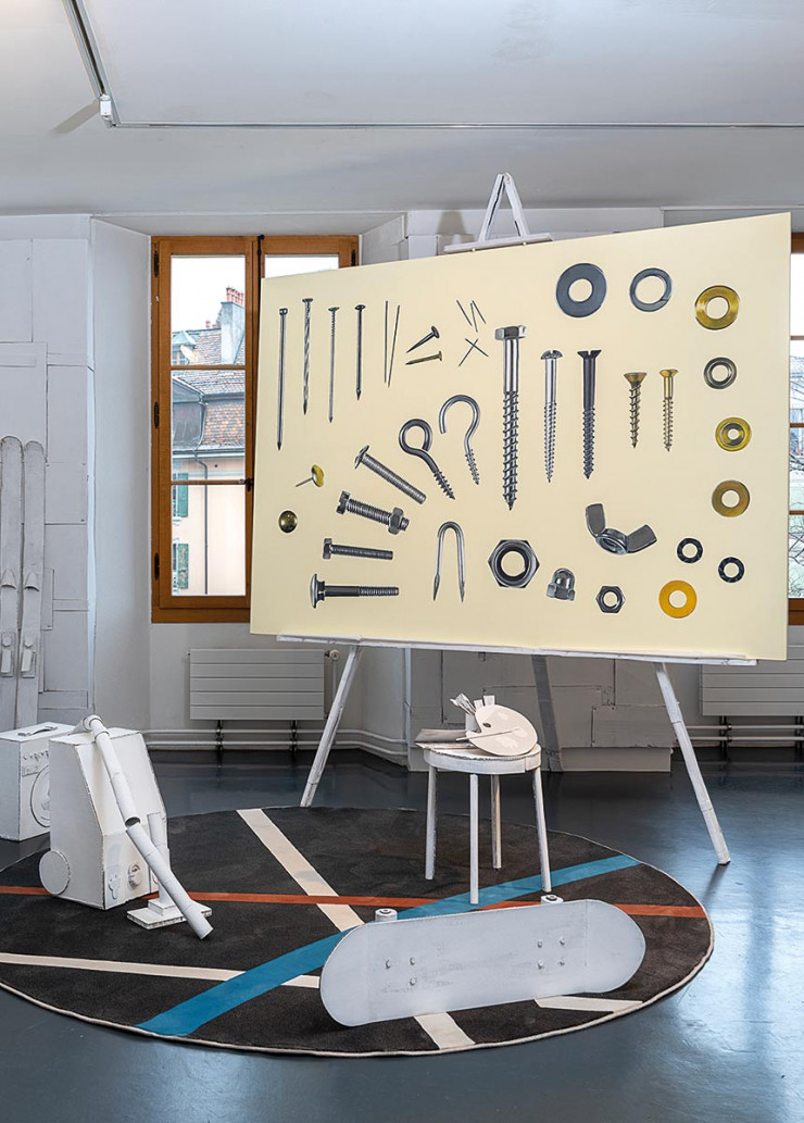 Dans le garage, parmi les objets en carton recyclé peint en blanc créés par le scénographe Sébastien Guenot, le tableau Vis (2011), de Vincent Kohler, et le tapis Carpet Athletica 2 (2018), de Schoenstaub.