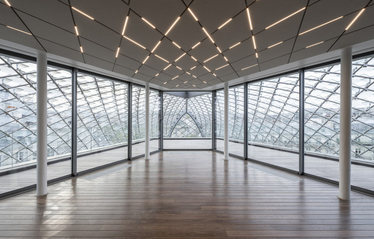 Ajourée et équipée d’écailles photovoltaïques, la nouvelle verrière englobe deux salles de réunion ouvrant chacune sur un deck.