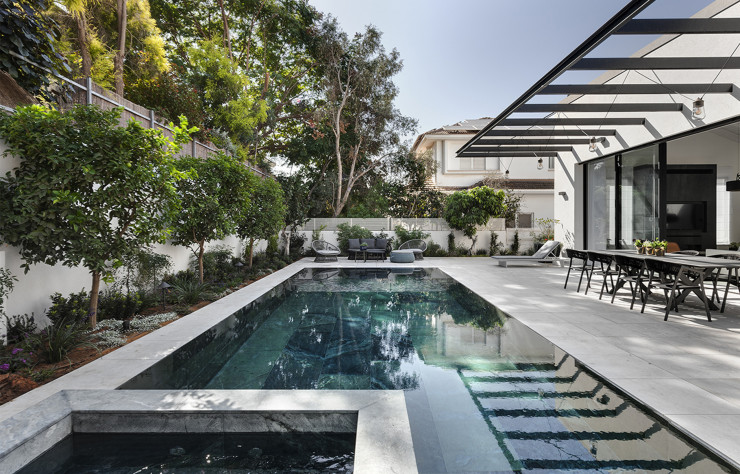 Au rez-de-chaussée, la maison s’ouvre sur une large terrasse extérieure avec son espace salle à manger, au bord d’une piscine.
