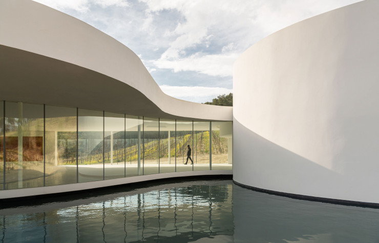 Le pavillon d’Oscar Niemeyer réunit plusieurs caractéristiques que l’on retrouve dans son travail architectural : plan d’eau-miroir, galerie, colonnade, courbes, transparence…