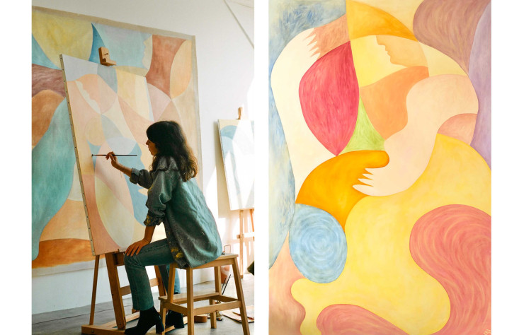 À gauche, la peintre Zahra Holm applique des touches de peinture sur une toile. À droite, l’oeuvre Alive I évoque un paysage marin dans lequel les nuances dorées du soleil épousent les bleus de la mer.